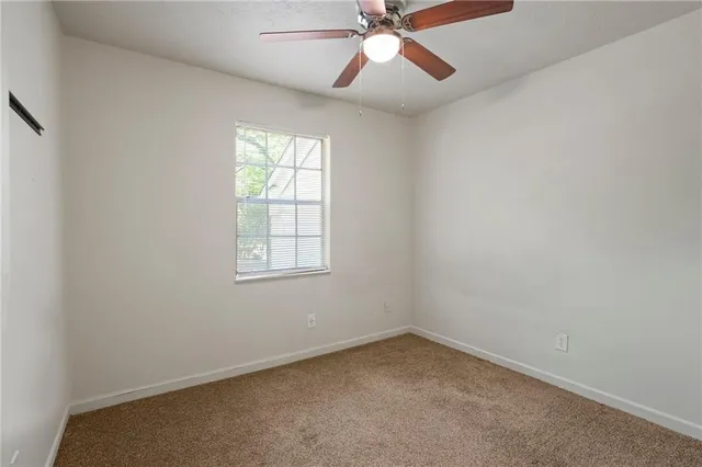 an empty room with a window and a fan