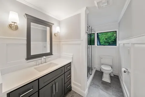 a bathroom with a sink a toilet a window and a mirror