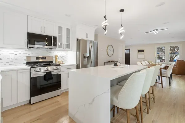 a large kitchen with stainless steel appliances a stove a sink dishwasher a microwave oven with a dining table and chairs