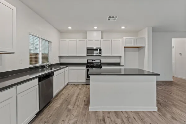 a large kitchen with stainless steel appliances granite countertop a stove a sink and a microwave