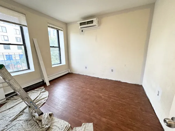 an empty room with wooden floor and windows