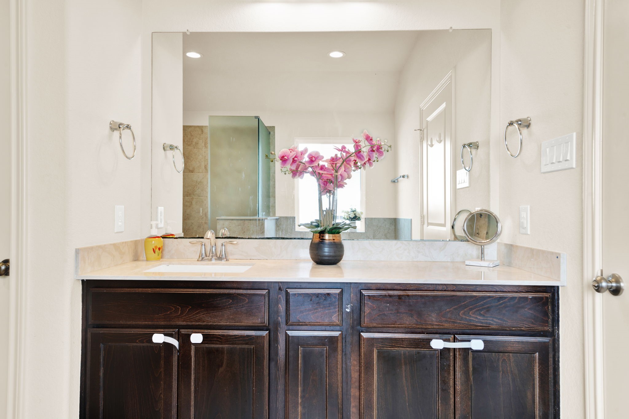 2503 Hagerman Road Conroe, TX 77384 - Photo 19 of 43 This bathroom features a modern vanity with a large mirror, dark wood cabinetry, and a sleek countertop.