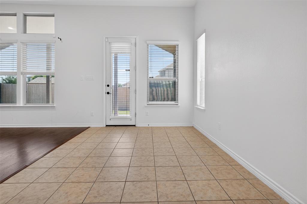 8728 Maple Ridge Trail Fort Worth, TX 76244 - Photo 17 of 40 Bright interior space featuring a glass-paneled door, multiple windows, and a combination of square tile flooring and dark wood-finish flooring