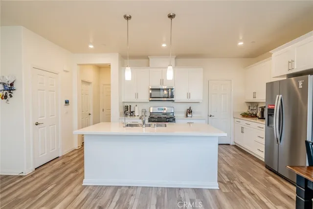 a large kitchen with stainless steel appliances a large counter top a sink a refrigerator and a window