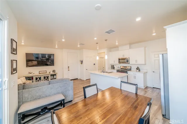a living room with stainless steel appliances kitchen island furniture and a dining table with wooden floor