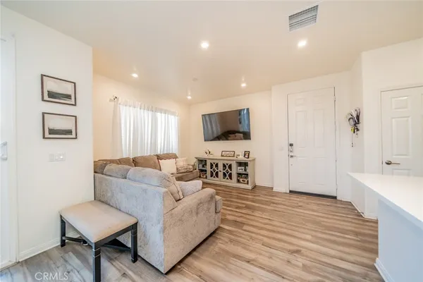 a living room with furniture a flat screen tv and kitchen view