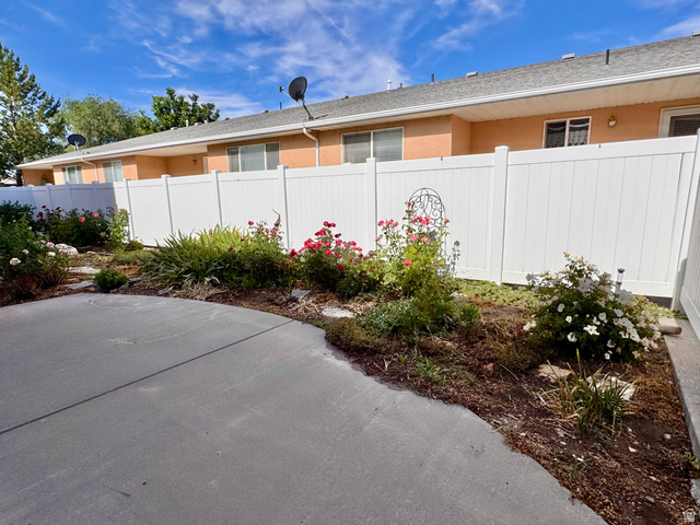 461 Topaz Boulevard, Unit 6 Delta, UT 84624 - Photo 32 of 45 Patio area bordered by a planted garden featuring blooming shrubs and a white privacy fence.