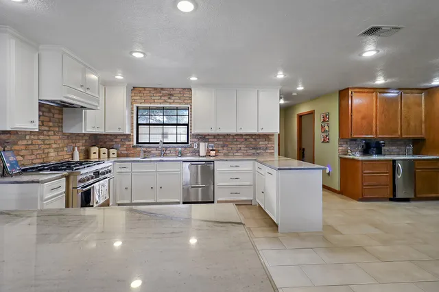 a large kitchen with granite countertop a stove top oven a sink a counter space and cabinets
