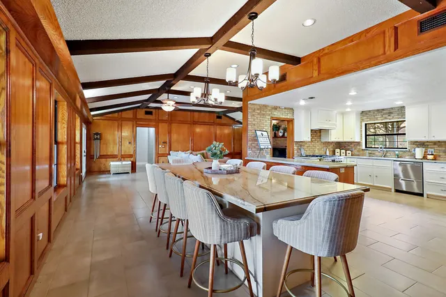 a dining hall with stainless steel appliances kitchen island granite countertop a table and chairs