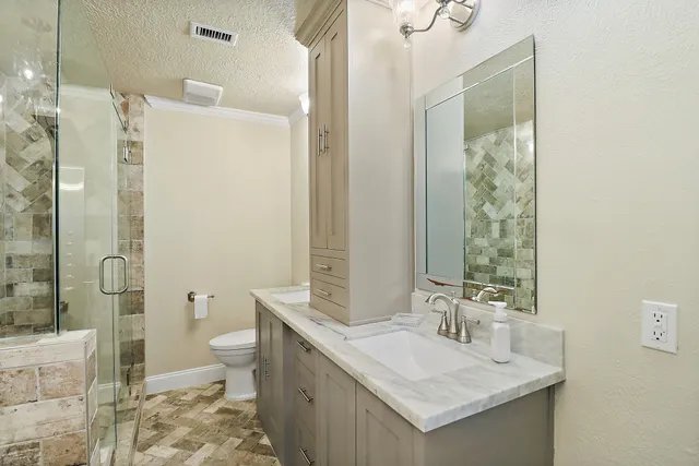 a bathroom with a granite countertop sink toilet and shower