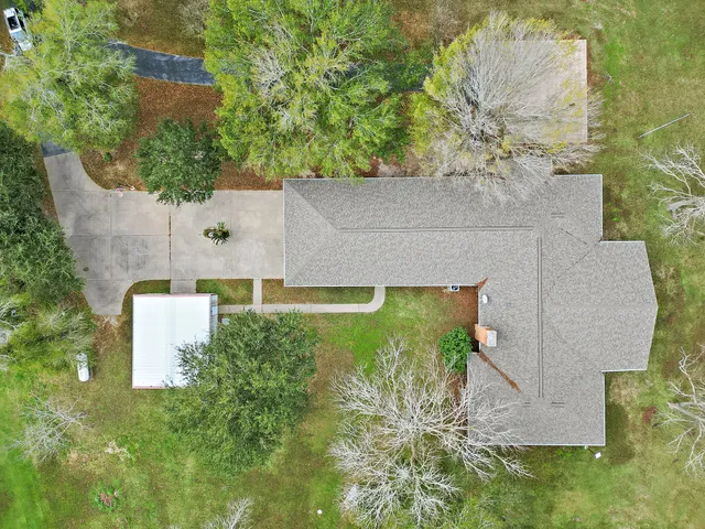 an aerial view of a house with a yard and trees all around