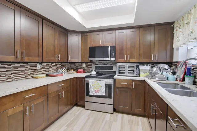 a kitchen with stainless steel appliances granite countertop wooden cabinets a sink and dishwasher a stove top oven with wooden floor