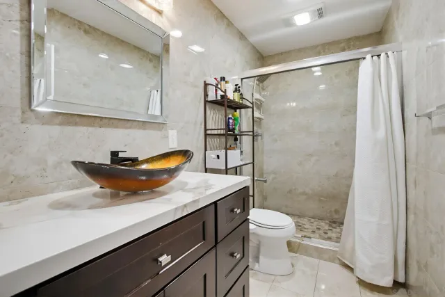 a bathroom with a granite countertop sink a toilet a shower and a mirror