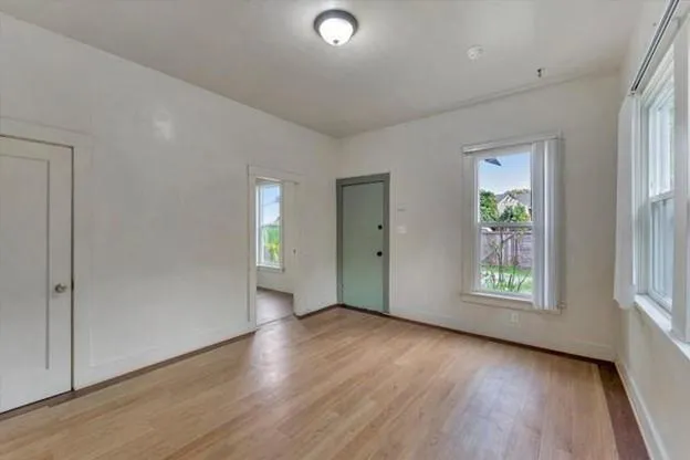 an empty room with wooden floor and windows