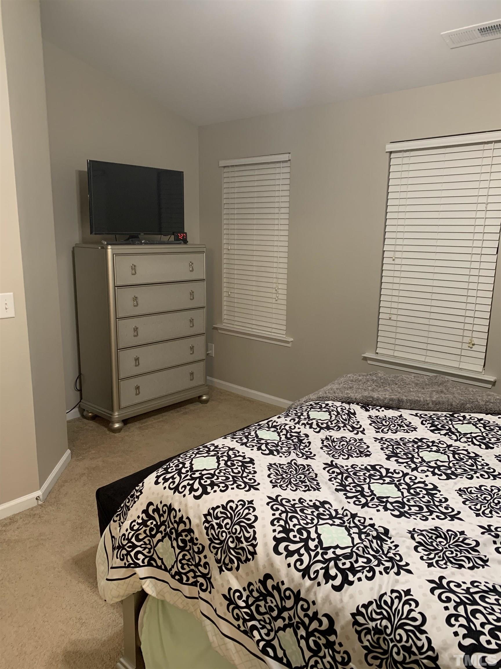 7845 Spungold Street Raleigh, NC 27617 - Photo 22 of 37 a bedroom with a bed and flat screen tv