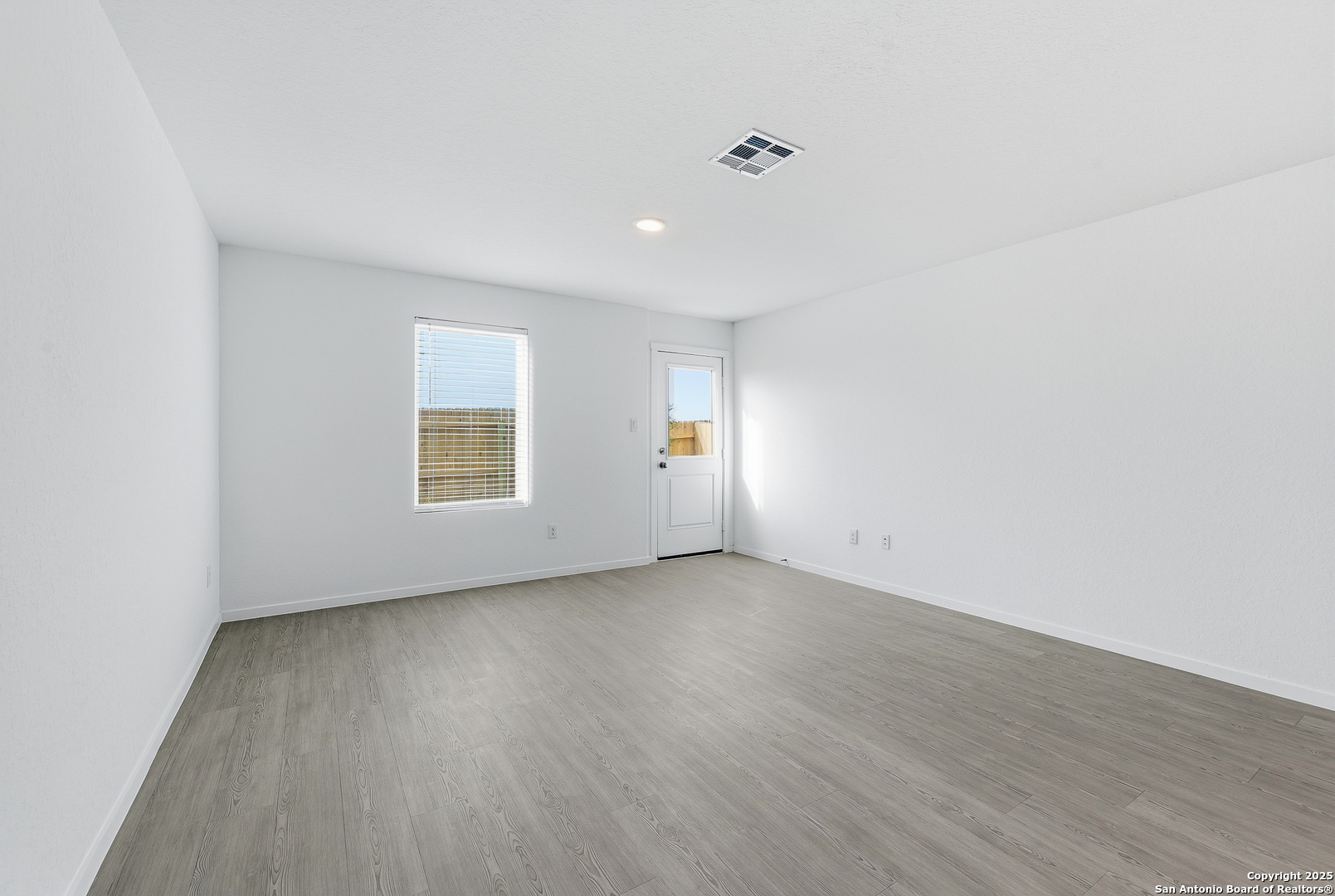 11814 Bluebell Ridge Converse, TX 78109 - Photo 9 of 20 an empty room with wooden floor and windows