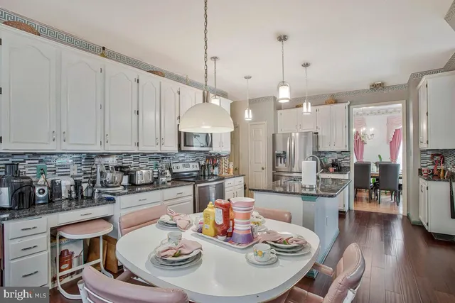 a kitchen with stainless steel appliances granite countertop a sink a stove a dining table and chairs