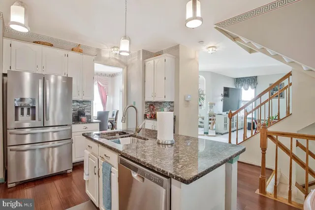 a kitchen with stainless steel appliances granite countertop a kitchen island a stove a refrigerator a oven and a dining table with wooden floor