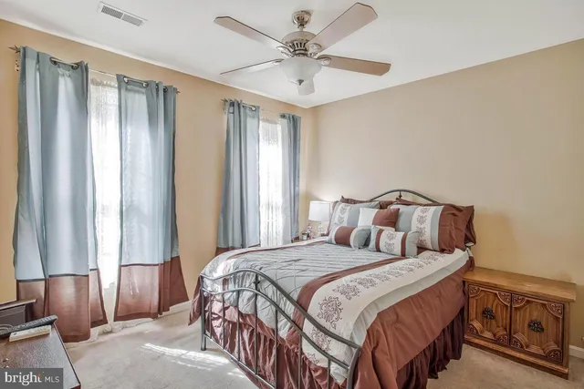 a bedroom with a large bed and a chandelier fan