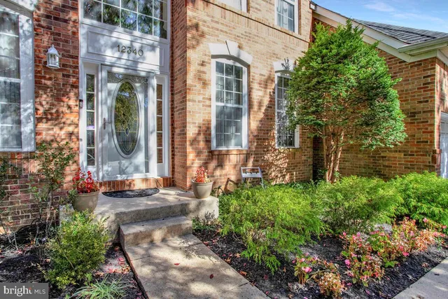 front view of a brick house with a large windows and a yard