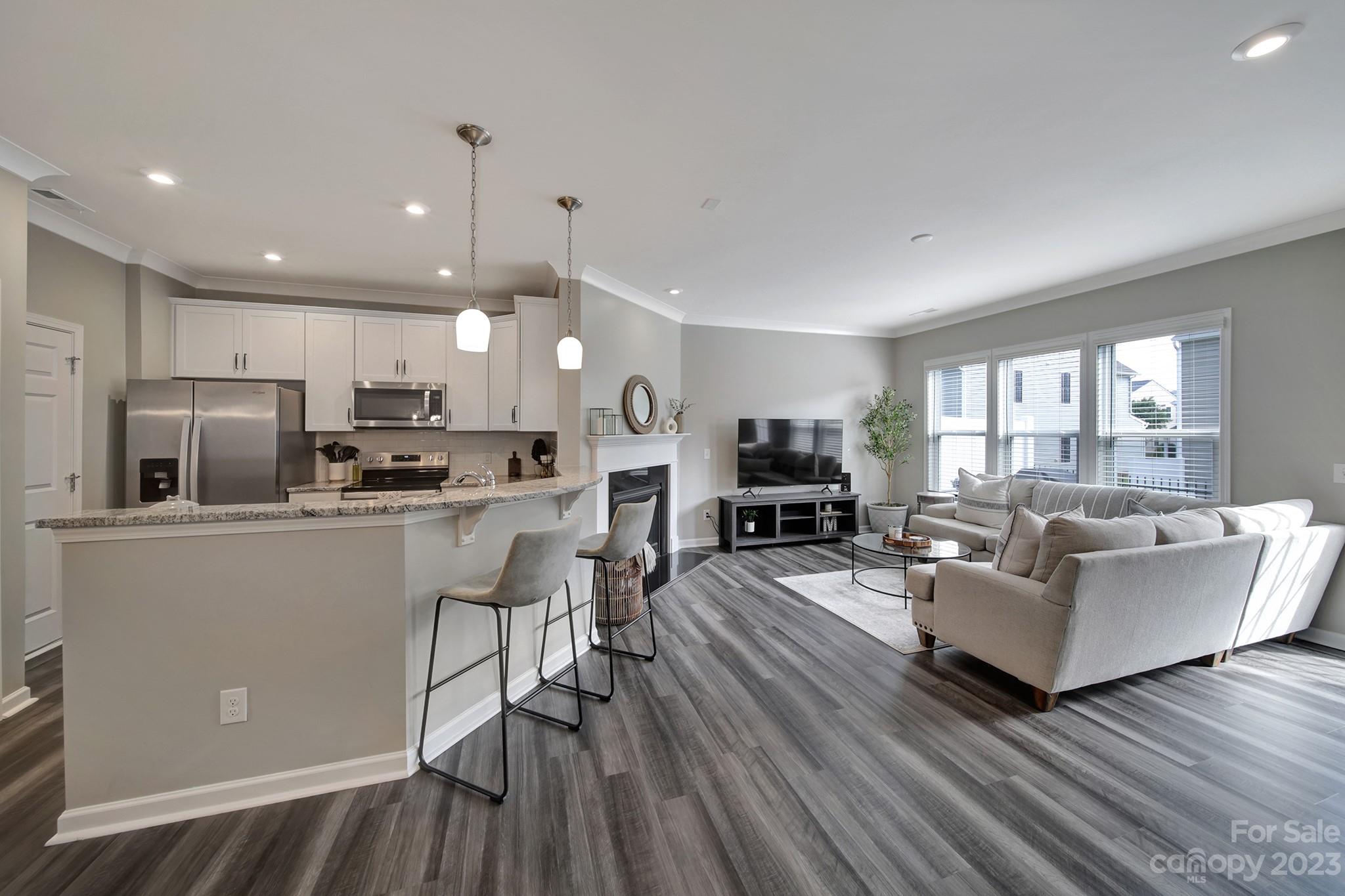 816 Canoe Song Road Fort Mill, SC 29708 - Photo 5 of 24 a living room with stainless steel appliances kitchen island granite countertop wooden floor a dining table and chairs