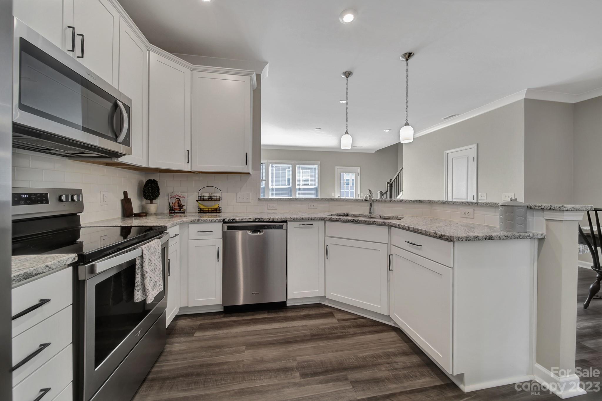 816 Canoe Song Road Fort Mill, SC 29708 - Photo 6 of 24 a kitchen with stainless steel appliances granite countertop a sink a stove a microwave oven a refrigerator with white cabinets and wooden floor