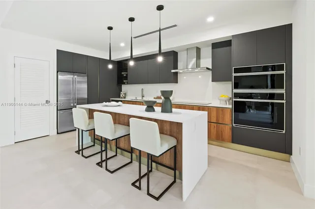 a kitchen with stainless steel appliances kitchen island a table chairs in it and wooden floors