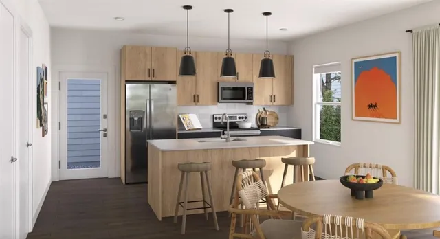 a kitchen with stainless steel appliances granite countertop a stove a refrigerator and a dining table with wooden floor