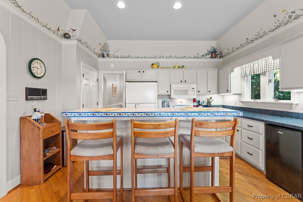 184 York Road Irvington, VA 22480 - Photo 18 of 46 Kitchen with a kitchen breakfast bar, white cabinets, light hardwood / wood-style floors, and white appliances