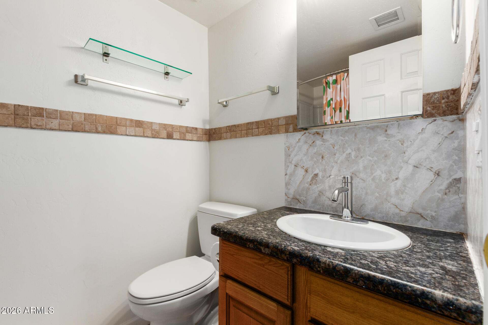 151 East Broadway Road, Unit 103 Tempe, AZ 85282 - Photo 19 of 33 a bathroom with a granite countertop sink a toilet a mirror and vanity