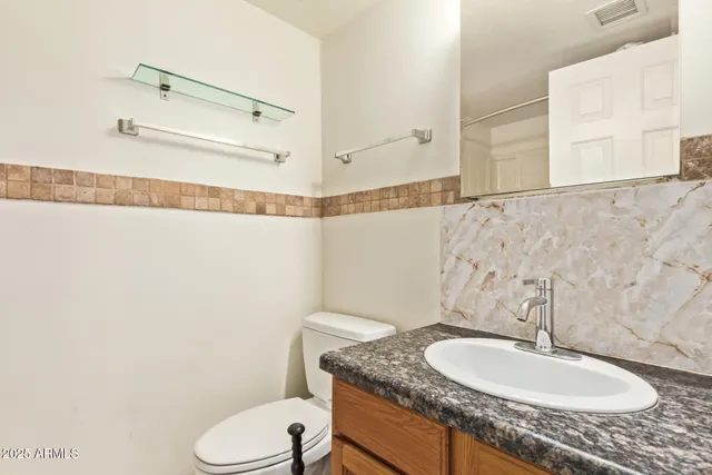 a bathroom with a granite countertop sink mirror vanity and toilet