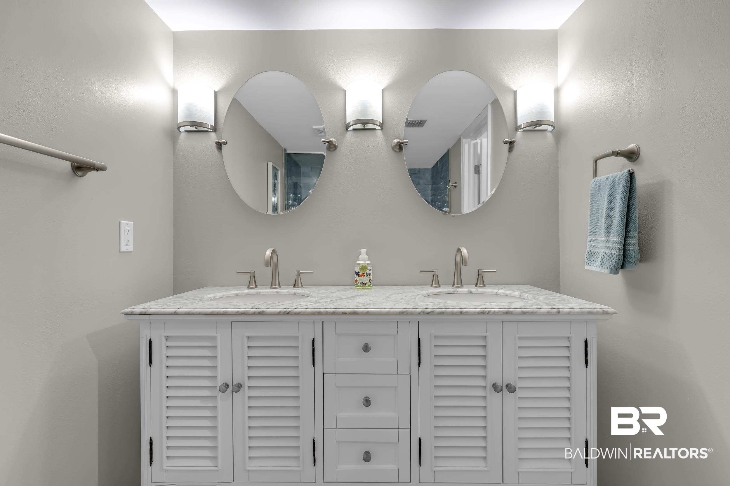 14100 River Road, Unit 211 Pensacola, FL 32507 - Photo 28 of 56 Double vanity featuring white shaker-style cabinetry with louvered doors, a light-toned countertop, and dual oval mirrors