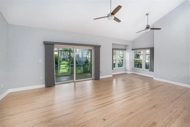 a view of an empty room with wooden floor and fan