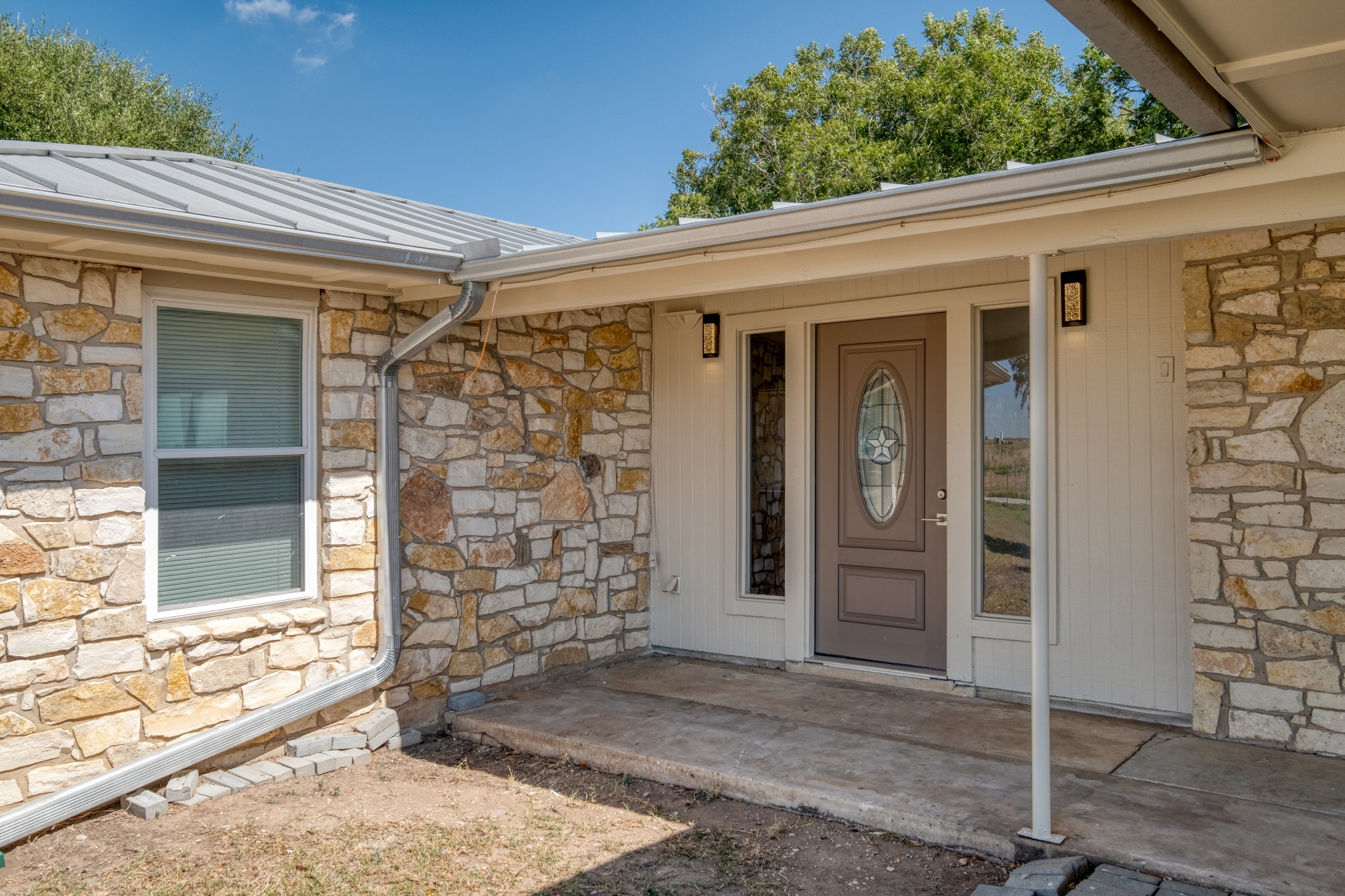 20960 Cameron Road Coupland, TX 78615 - Photo 4 of 21 A welcoming front porch features rustic stone accents and a metal roof.