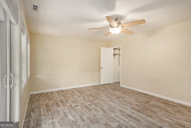 a view of empty room with wooden floor and ceiling fan