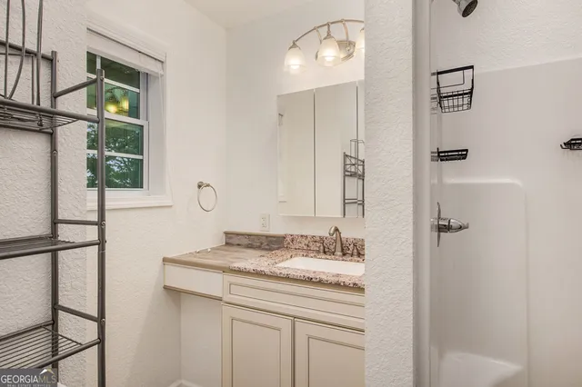 a bathroom with a granite countertop sink and a mirror