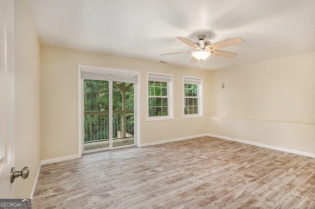 an empty room with wooden floor fan and windows