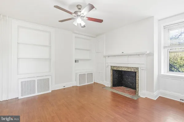 a view of empty room with fireplace and wooden floor