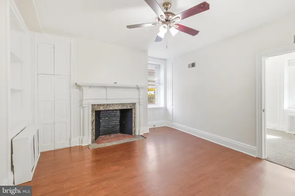 a view of a livingroom with a fireplace a ceiling fan and wooden floor
