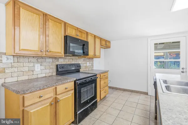 a kitchen with granite countertop a stove a sink and a microwave