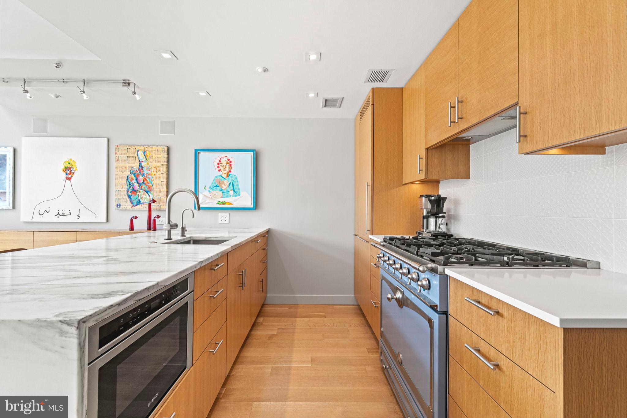 912 F Street Northwest, Unit 1100 Washington, DC 20004 - Photo 9 of 23 a large kitchen with stainless steel appliances granite countertop a stove and a sink