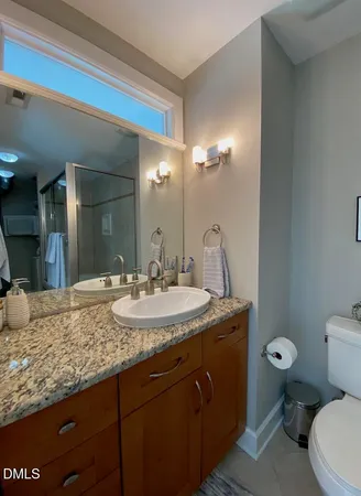 a bathroom with a granite countertop sink a toilet and a mirror