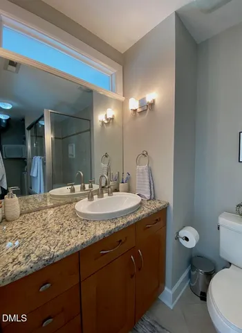 a bathroom with a granite countertop sink a toilet and a mirror
