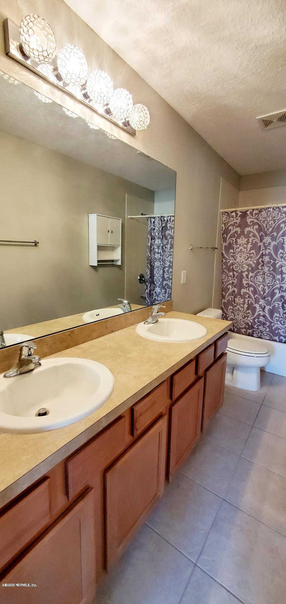 1500 Calming Water Drive, Unit 1003 Fleming Island, FL 32003 - Photo 6 of 13 a spacious bathroom with a granite countertop sink and a mirror