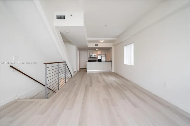 a view of a hallway with wooden floor and staircase