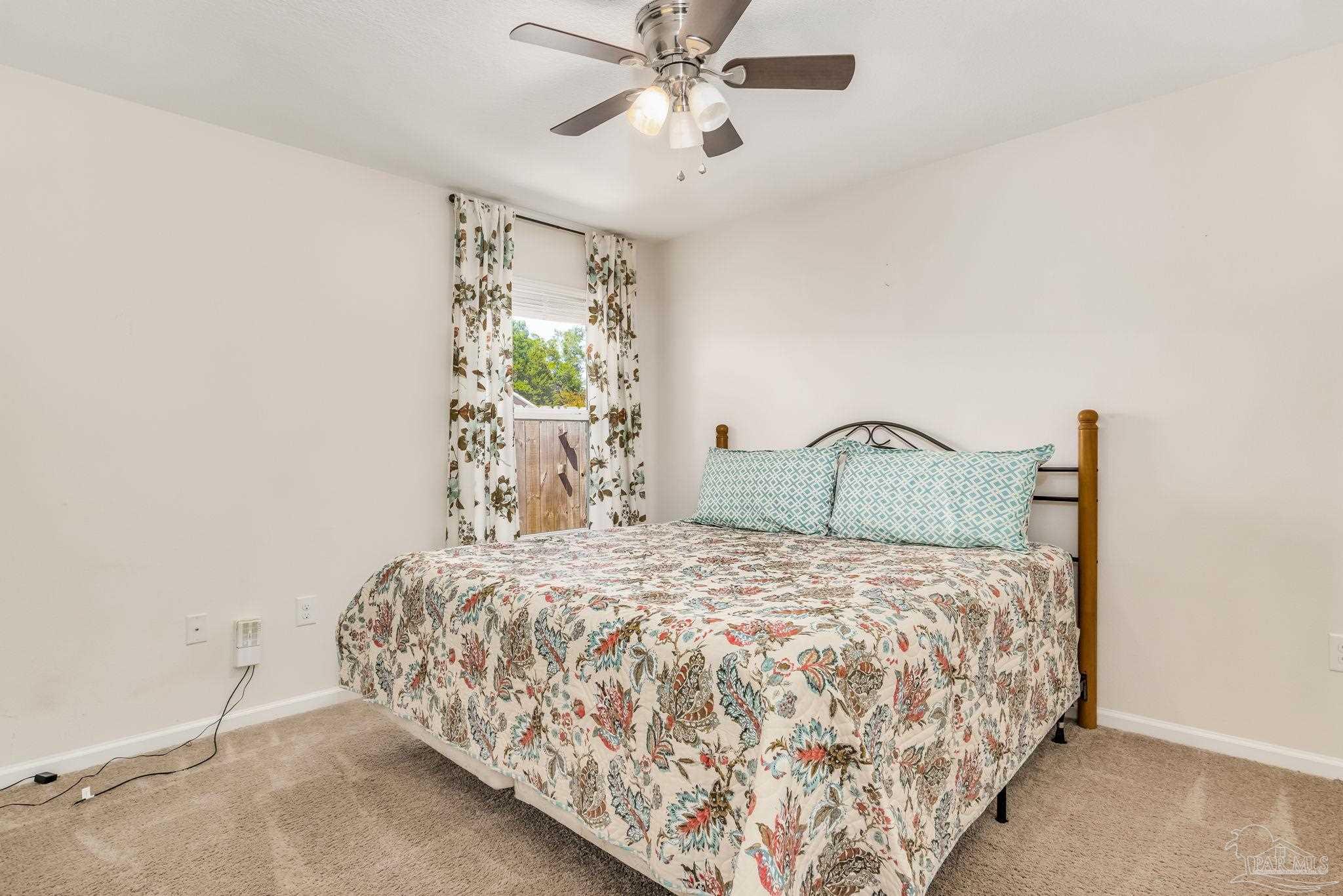 4706 Apple Field Way Milton, FL 32571 - Photo 30 of 52 a bed sitting in a bedroom next to a window and a chandelier