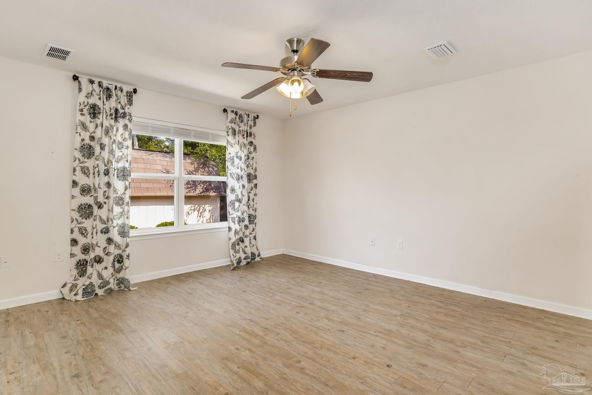 4706 Apple Field Way Milton, FL 32571 - Photo 38 of 52 a view of an empty room with a window and wooden floor
