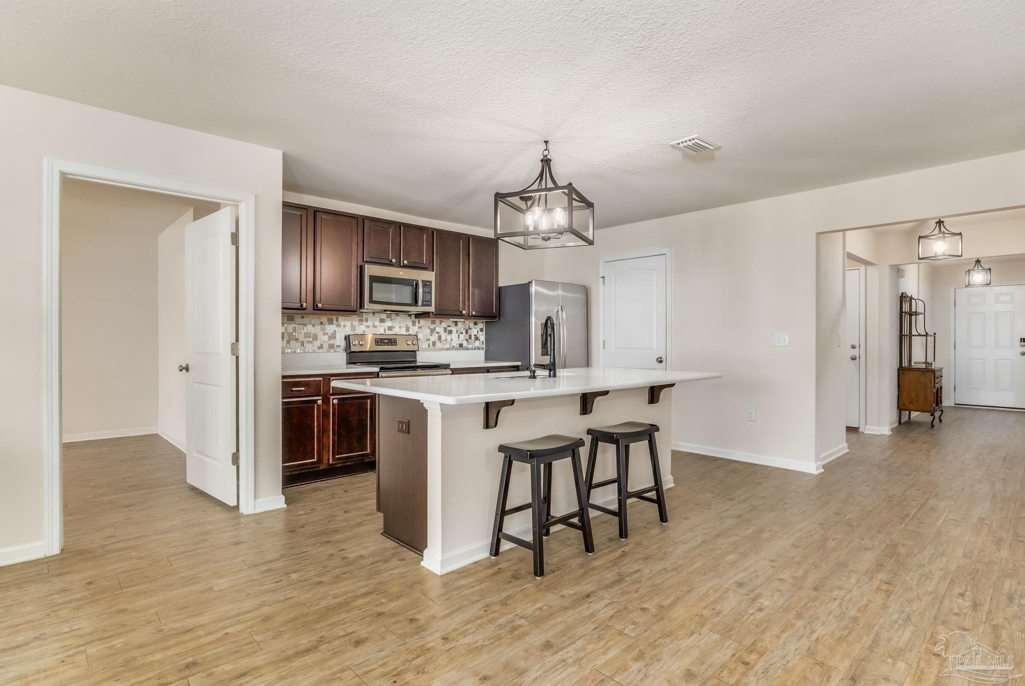 4706 Apple Field Way Milton, FL 32571 - Photo 4 of 52 a kitchen with kitchen island granite countertop a sink cabinets and stainless steel appliances