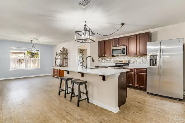 a kitchen with kitchen island granite countertop a sink cabinets a window and stainless steel appliances
