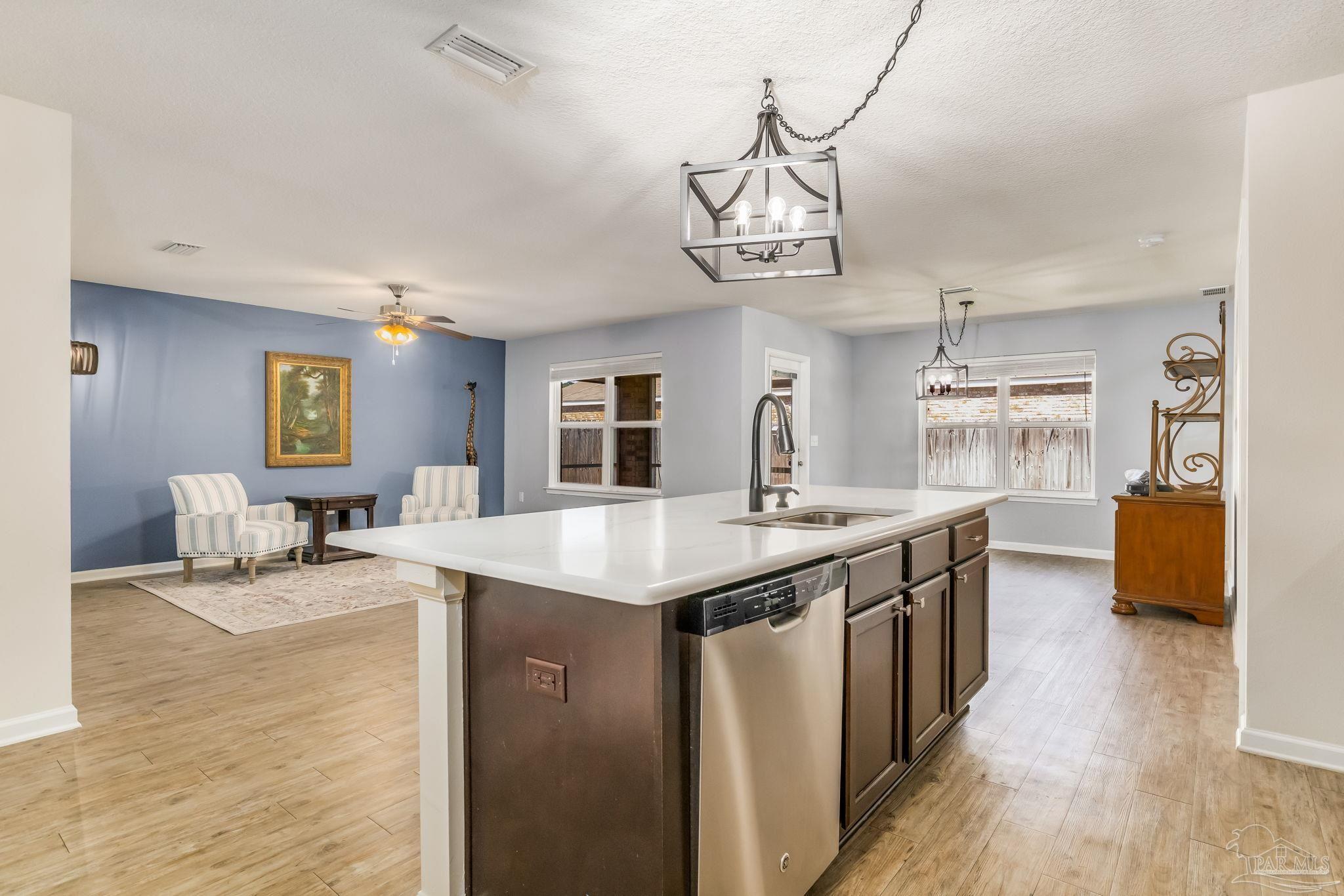 4706 Apple Field Way Milton, FL 32571 - Photo 6 of 52 a kitchen with stainless steel appliances granite countertop a sink dishwasher cabinets a dining table and chairs with wooden floor